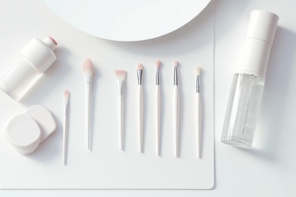 Ergonomically designed makeup brushes and a specialized cleaner solution on a sleek, modern vanity.